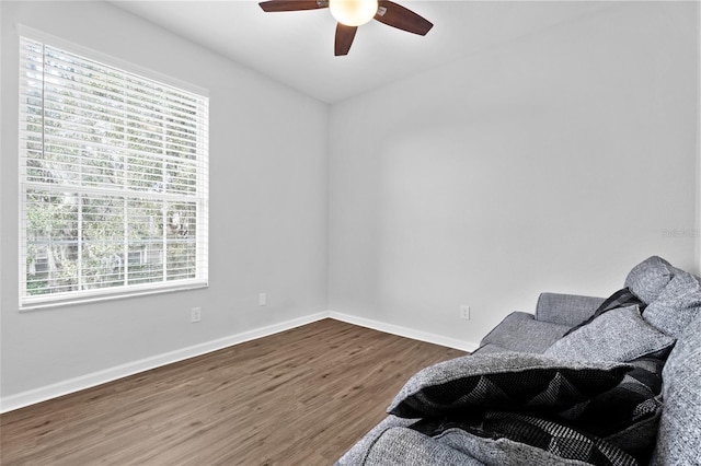 living area featuring ceiling fan, baseboards, and dark wood-type flooring