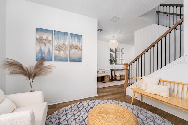 entrance foyer featuring a textured ceiling, stairway, wood finished floors, and visible vents