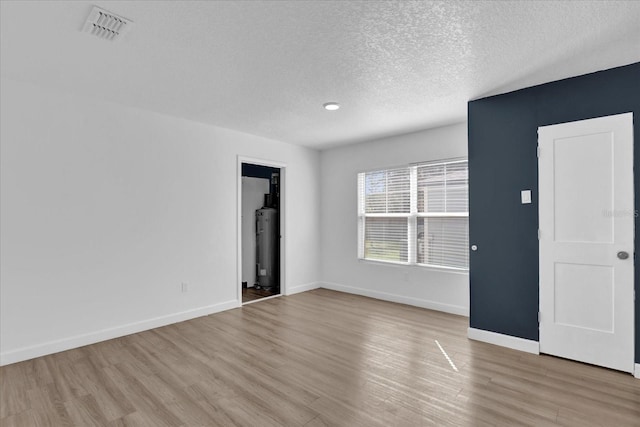 unfurnished room with light wood-type flooring, visible vents, and baseboards