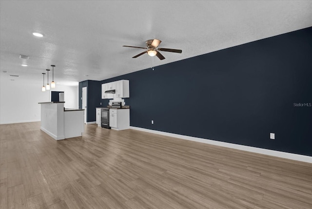 unfurnished living room with a ceiling fan, baseboards, a textured ceiling, and light wood finished floors