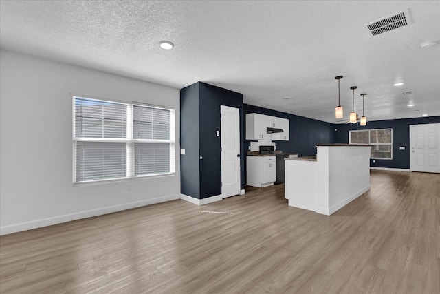 kitchen featuring visible vents, white cabinets, open floor plan, decorative light fixtures, and range with electric stovetop