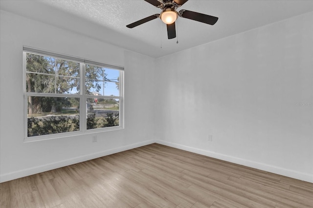 spare room featuring baseboards, ceiling fan, and light wood-style floors