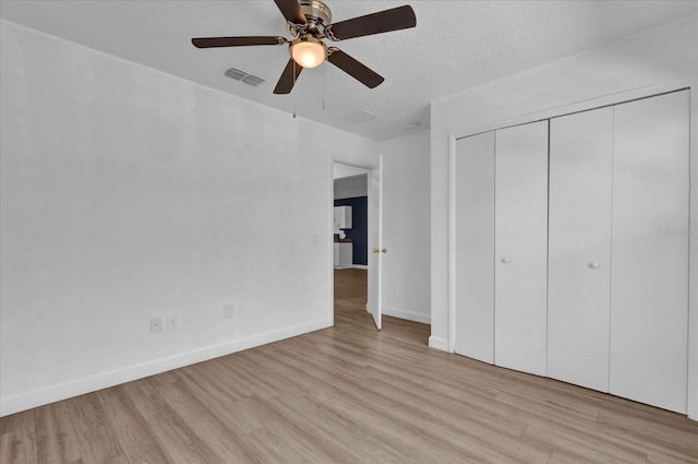 unfurnished bedroom featuring baseboards, visible vents, ceiling fan, light wood-style floors, and a closet