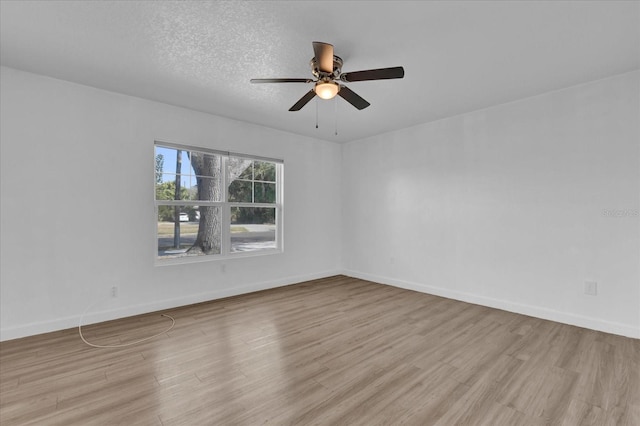 empty room with baseboards, ceiling fan, a textured ceiling, and light wood-style floors