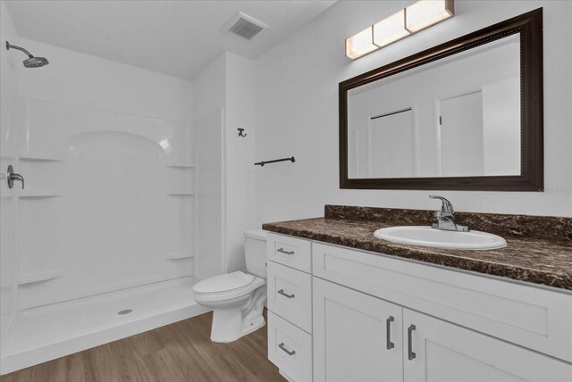 bathroom featuring visible vents, toilet, a shower stall, vanity, and wood finished floors