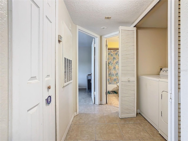 laundry area with light tile patterned floors, a textured ceiling, washer and dryer, laundry area, and baseboards