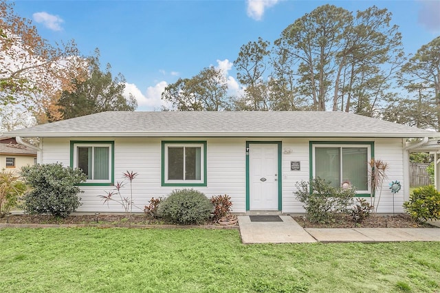 ranch-style home featuring a shingled roof and a front lawn