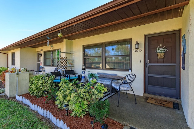 property entrance with covered porch and stucco siding