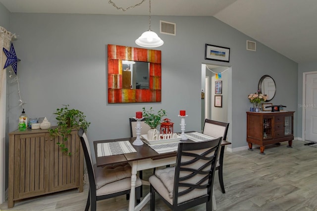 dining room featuring light wood-style floors, lofted ceiling, radiator, and visible vents