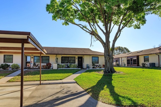 view of front of property with a front lawn, central AC unit, and stucco siding