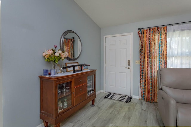 entrance foyer featuring lofted ceiling, light wood-style flooring, and baseboards