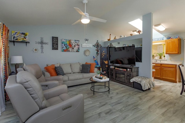 living area featuring lofted ceiling, light wood finished floors, and a ceiling fan