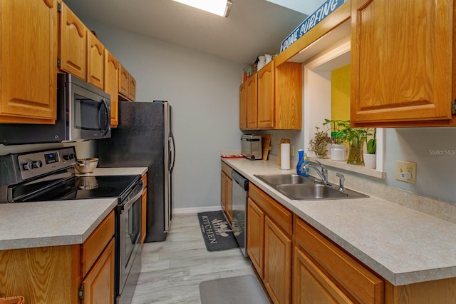 kitchen with light countertops, appliances with stainless steel finishes, brown cabinetry, and a sink