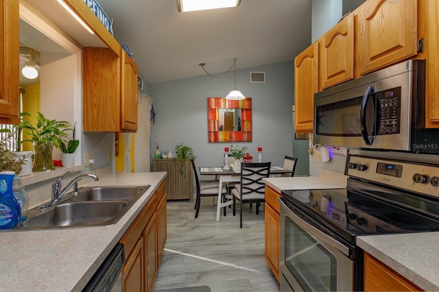 kitchen with lofted ceiling, light countertops, appliances with stainless steel finishes, and a sink