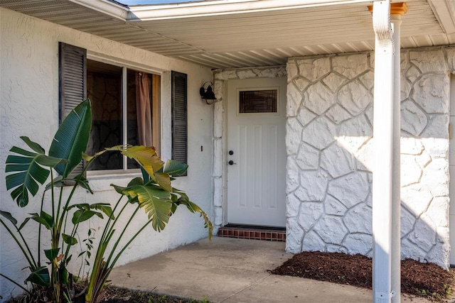 view of exterior entry featuring stone siding and stucco siding