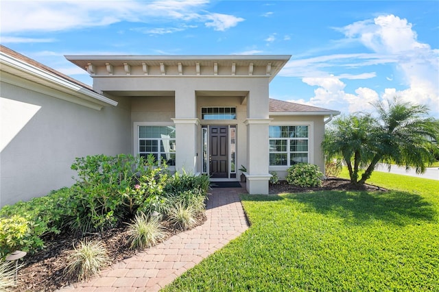 doorway to property featuring a yard and stucco siding