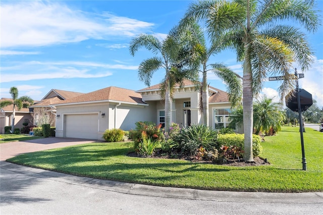 view of front of home featuring a garage, decorative driveway, a front lawn, and stucco siding