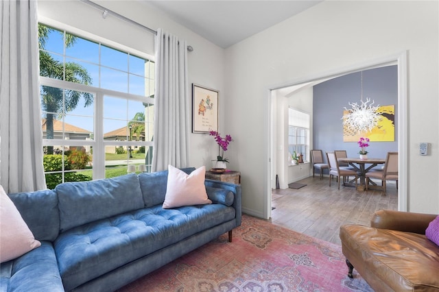 living area featuring a chandelier, wood finished floors, and baseboards