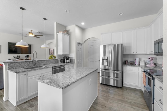 kitchen with light wood-style flooring, a peninsula, a sink, white cabinets, and appliances with stainless steel finishes