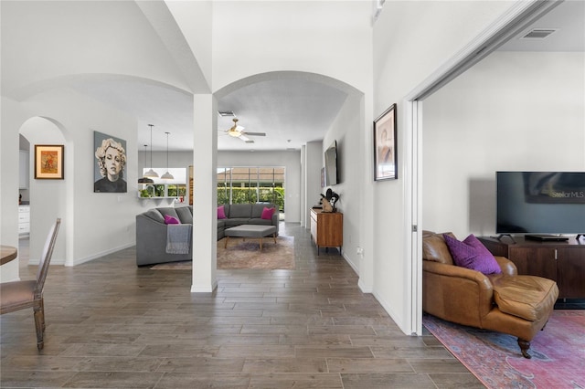 entryway with arched walkways, wood finished floors, visible vents, a ceiling fan, and baseboards