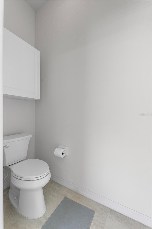 bathroom featuring toilet, baseboards, and tile patterned floors