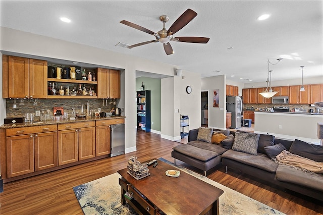 living room with indoor wet bar, recessed lighting, ceiling fan, wood finished floors, and baseboards