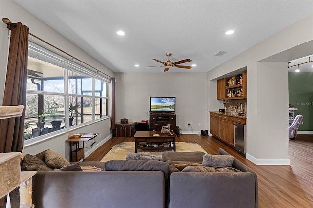 living area featuring recessed lighting, visible vents, a bar, wood finished floors, and baseboards