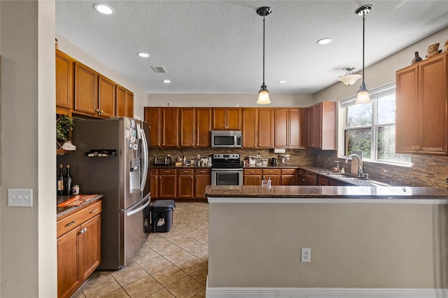 kitchen with visible vents, decorative backsplash, appliances with stainless steel finishes, a sink, and a peninsula