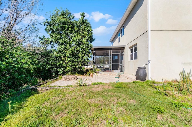 view of yard featuring an outdoor fire pit, a sunroom, and a patio