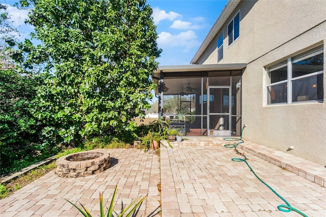 view of patio featuring an outdoor fire pit and a sunroom