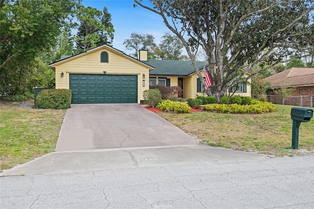 ranch-style home featuring a chimney, an attached garage, a front yard, fence, and driveway