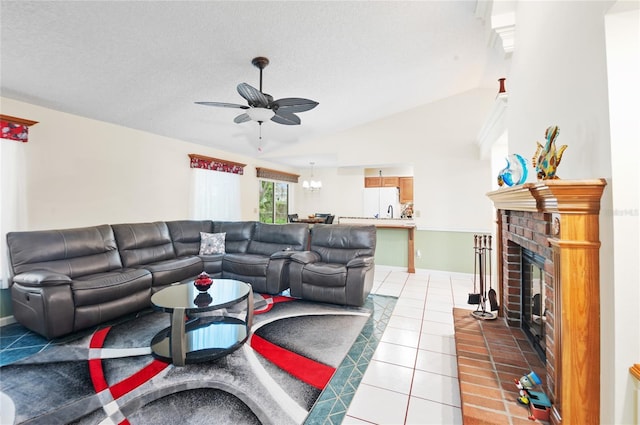 tiled living room with lofted ceiling, a fireplace, a textured ceiling, and ceiling fan with notable chandelier