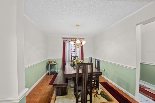 dining room with crown molding, a textured ceiling, baseboards, and a notable chandelier