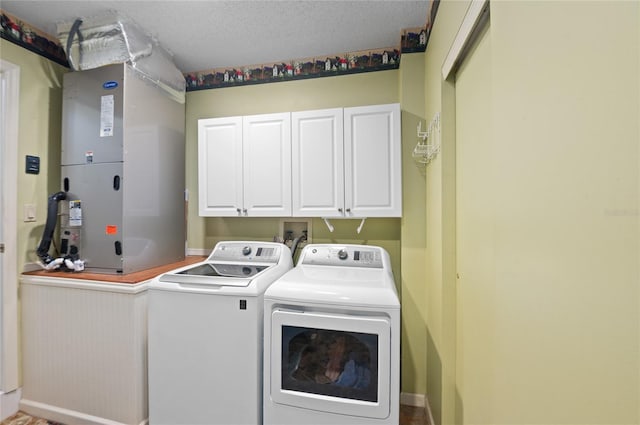 laundry room featuring heating unit, cabinet space, a textured ceiling, and washer and dryer