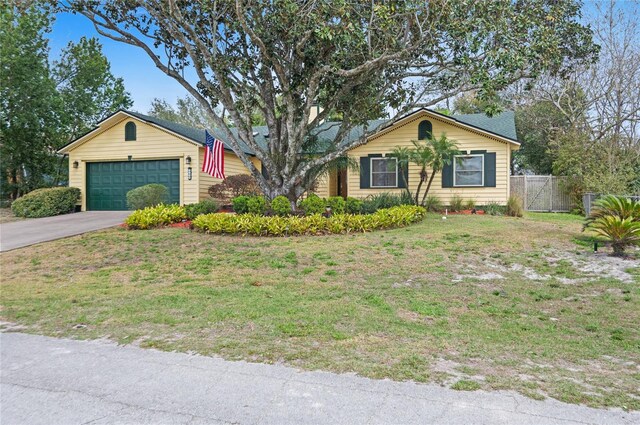 ranch-style house featuring an attached garage, fence, a front lawn, and concrete driveway