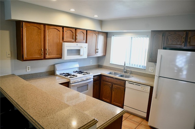 kitchen featuring white appliances, brown cabinets, light countertops, a sink, and recessed lighting