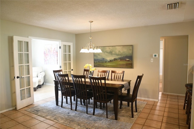 dining room featuring light tile patterned floors, a textured ceiling, an inviting chandelier, and french doors