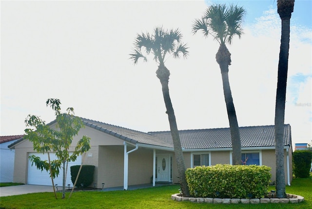 ranch-style house featuring a garage, a tiled roof, a front lawn, and stucco siding