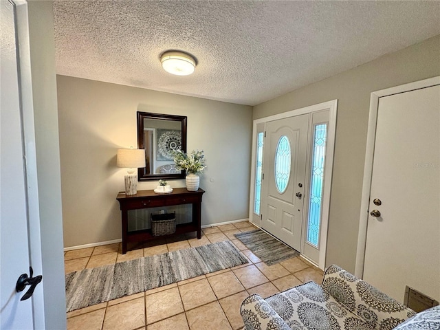 foyer entrance featuring light tile patterned floors, baseboards, and a textured ceiling