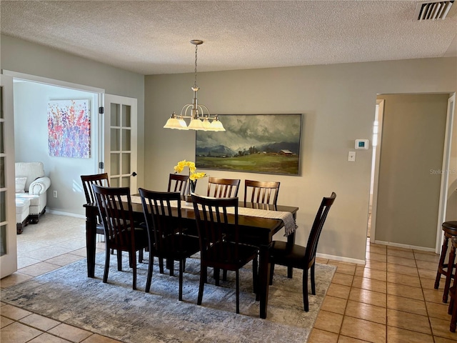 dining area with an inviting chandelier, light tile patterned floors, visible vents, and a textured ceiling