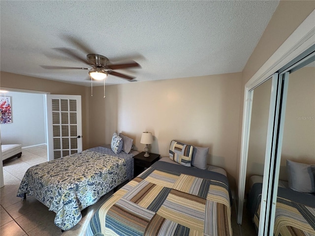 bedroom with light tile patterned floors, a textured ceiling, a ceiling fan, and a closet