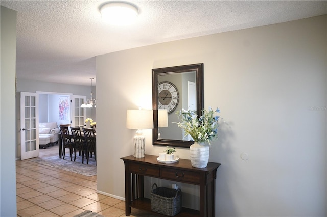 hallway featuring light tile patterned flooring, a textured ceiling, and french doors