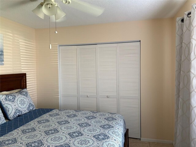 tiled bedroom with a textured ceiling, a ceiling fan, and a closet