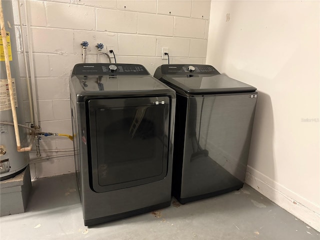 laundry room with water heater, laundry area, concrete block wall, and washer and dryer