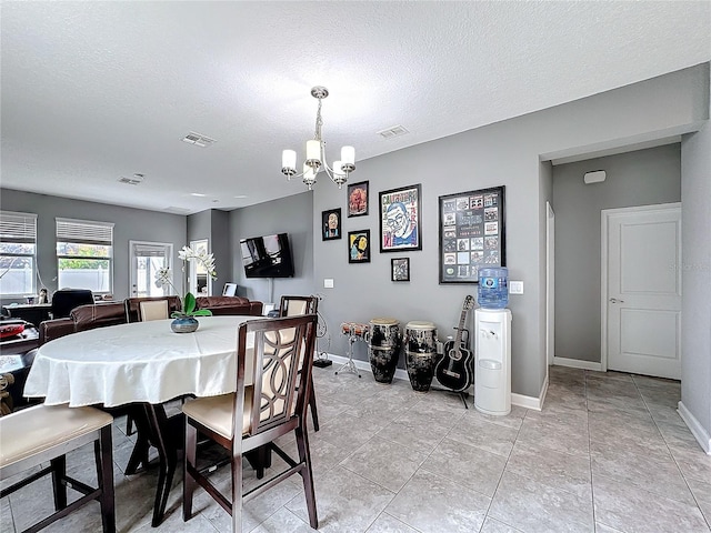 dining area featuring a textured ceiling, an inviting chandelier, visible vents, and baseboards