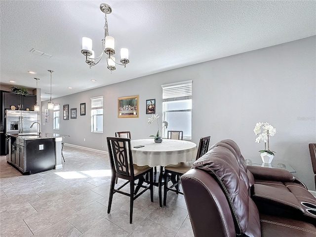 dining space with a textured ceiling, baseboards, visible vents, and a notable chandelier