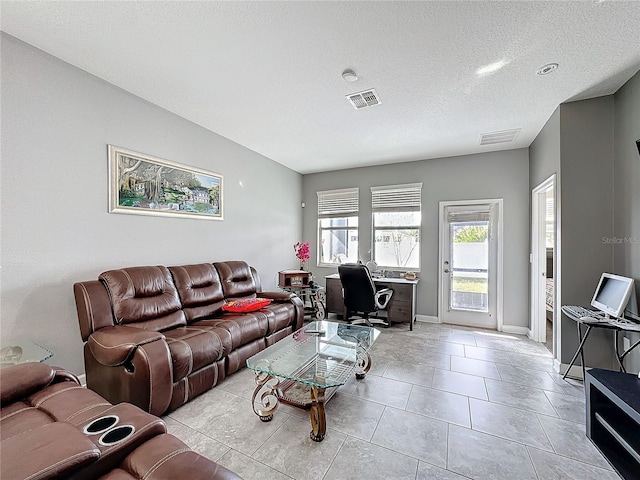 living area with light tile patterned floors, baseboards, visible vents, and a textured ceiling