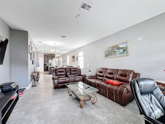 living area with light tile patterned floors, a textured ceiling, visible vents, and a notable chandelier