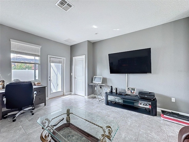 office area featuring light tile patterned floors, a textured ceiling, visible vents, and baseboards