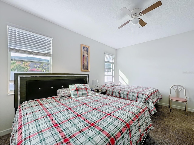 bedroom featuring a textured ceiling, ceiling fan, dark carpet, and baseboards